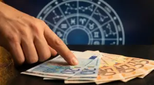 Mano che indica banconote in euro con sfondo di simboli zodiacali